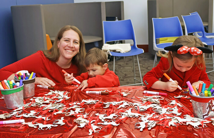 Angie Coderre sits with her children, Kate, 4, and Gabe, 2, as they color horse ornaments during the Flossmoor Public Library’s Lunar New Year celebration Saturday, Feb. 14. (Nuha Abdessalam/H-F Chronicle)