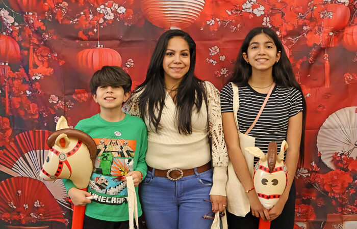 Rosalinda Ledesma poses with her children, Diego, 9, and Isabella, 12, in front of a photo backdrop during the library’s Lunar New Year celebration. (Nuha Abdessalam/H-F Chronicle)