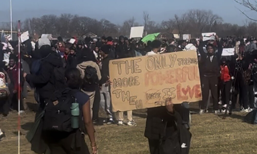 A Homewood-Flossmoor High School student with a sign that says "The only thing more powerful than hate is love," a reference to Bad Bunny's sign at the Super Bowl. (Nick Ulanowski/H-F Chronicle)