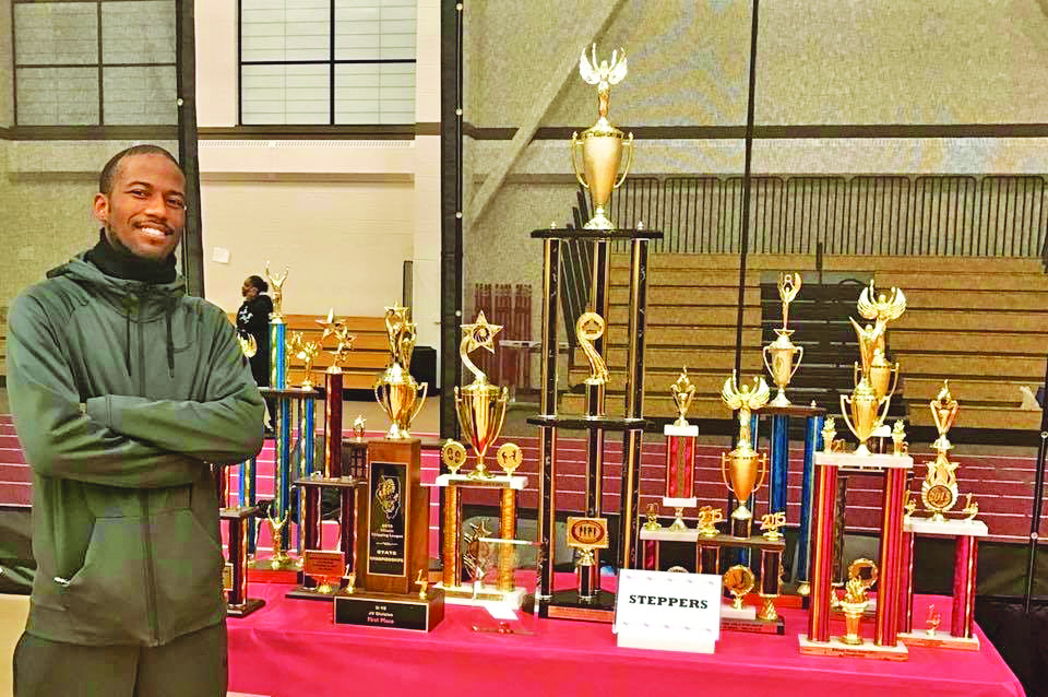 Jaron Boyd poses with a display of trophies won by the H-F Steppers during his tenure on the coaching staff. (Provided photo)