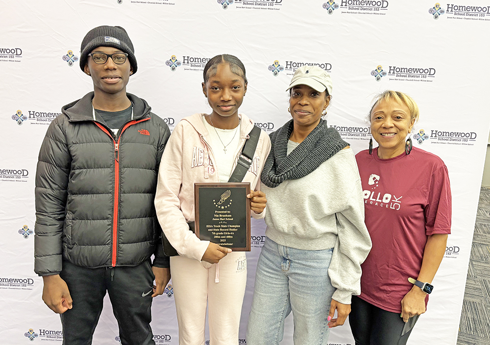 Nia Branham, second from left, an eighth grader at Hart School, holds her latest trophy. She set state records in the 200-meter and 400-meter races for the Illinois Elementary School Association competition. With her are, from left, her brother Nicholas, her mother Nona Branham and her cousin Annette Burke. (Marilyn Thoams/H-F Chronicle)