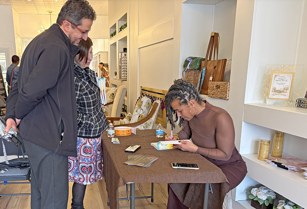 Dominica McBride, right, signs the "Becoming Change Makers" book for event attendees at Beyond the Book on March 7. (Jamilah Lewis/H-F Chronicle)