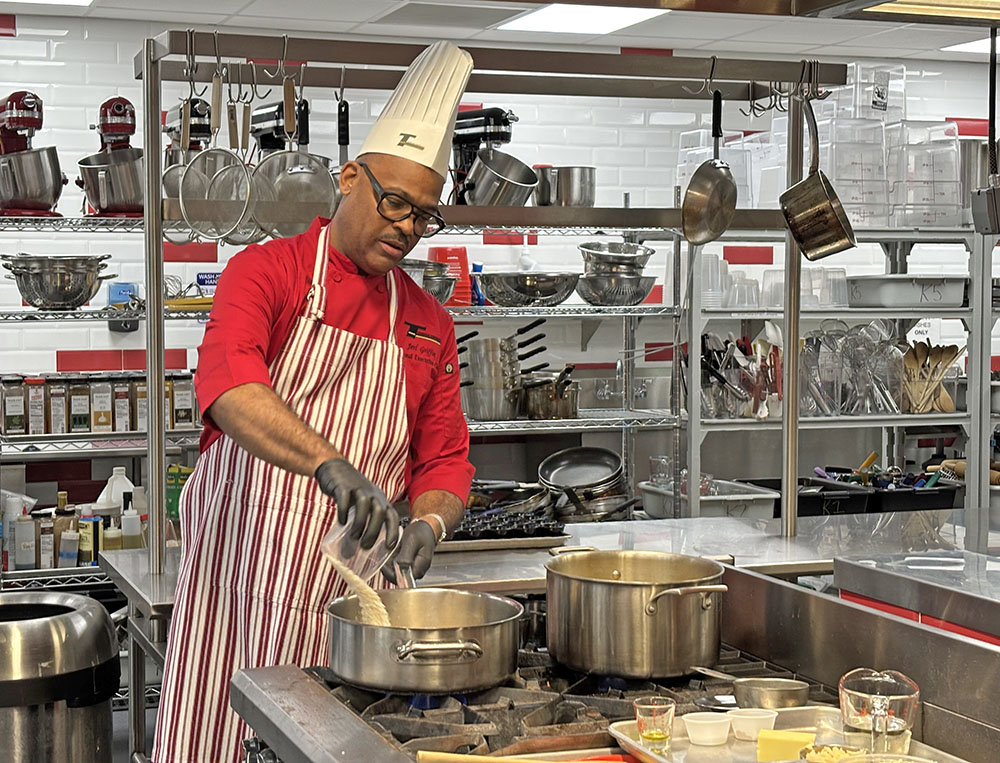 Chef Jerl Griffin pours arborio rice into a pot in the culinary lab at Homewood-Flossmoor High School. The alumnus talked about his profession as he prepared a dish for students. (Marilyn Thomas/H-F Chronicle)