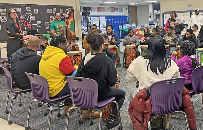 Teacher Jon Pettis, in the tan jacket, leads the drum circle at the Churchill School Black History month event on Feb. 26. Orchestra teacher Bryson Robinson-Levant and Churchill Elementary parent Laura Miller play instruments behind him. (Nick Ulanowski H-F Chronicle)