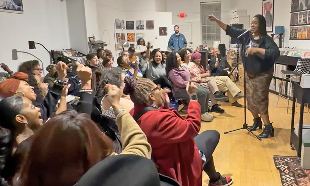 Theresa tha S.O.N.G.B.I.R.D. performs a song-poem hybrid and audience members singing along to the refrain, “All that Black Girl Magic.” (Nick Ulanowski / H-F Chronicle)