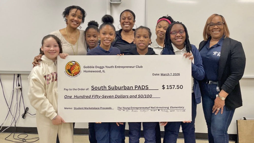 Neal Armstrong Elementary student Skylar Petritch, far left, Neal Armstrong Elementary teacher Latasha Davis, students Treasure House and Michelle Banjo, Gobble Dogs owner Annah Mitchell, students Cornelius Crossley Jr., Kaitlyn Perkins, Nia Greene and South Suburban PAD Shelter Operations Manager Rashida Hughes holding up the $157.50 check that the students donated to South Suburban PADS after a two-month entrepreneurship program and selling the products they made. (Provided photo)
