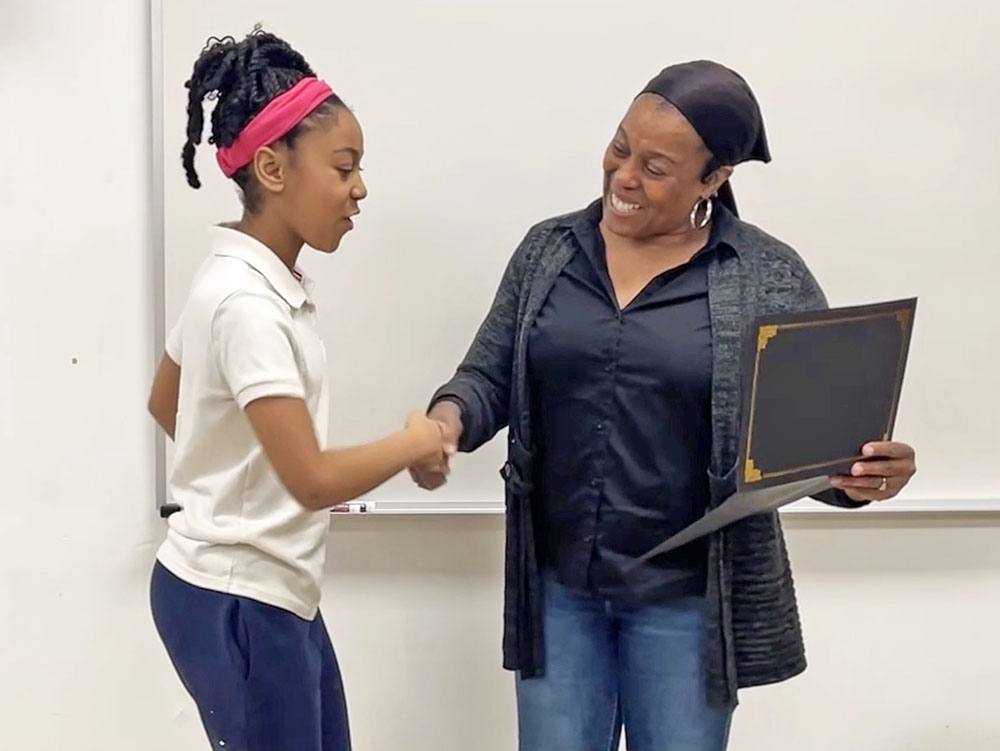 Neil Armstrong Elementary School student Kaitlyn Perkins, left, accepts her Certificate of Achievement for selling handmade bracelets and completing a student entrepreneurship program from Gobble Doggs owner Annah Mitchell. (Provided photo)