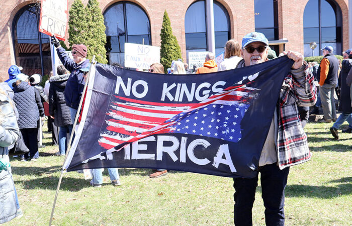 Al Reed holds a flag reading “NO KINGS IN AMERICA” during the rally in Homewood, where hundreds gathered along Harwood Avenue. (Nuha Abdessalam/H-F Chronicle)