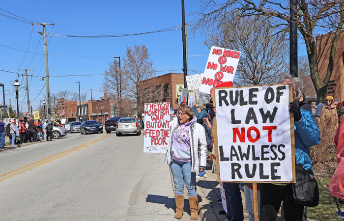 People line Harwood Avenue outside the Homewood Veterans Memorial, holding signs that read “Rule of Law Not Lawless Rule” and “No Kings” as the crowd stretches down the block. (Nuha Abdessalam/H-F Chronicle)