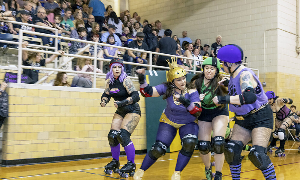 A member of the Punk Rock Punishers, in purple, elbows a skater from the Horrific Haunters, in green, during a roller derby bout in front of a sell-out crowd at H-F Auditorium on Saturday, April 15. The event was organized by Chicago Knockouts Roller Derby, which hosts monthly bouts at the Homewood venue. (Colin Thomas/Thomas Photographic Services)
