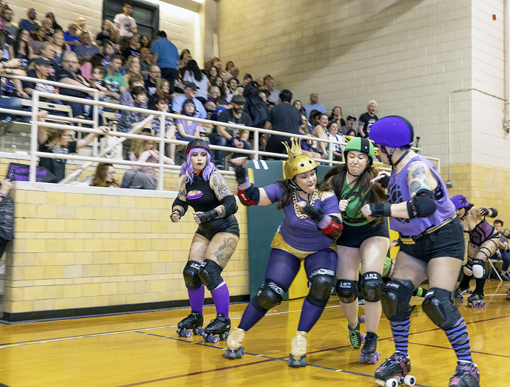 A member of the Punk Rock Punishers, in purple, elbows a skater from the Horrific Haunters, in green, during a roller derby bout in front of a sell-out crowd at H-F Auditorium on Saturday, April 15. The event was organized by Chicago Knockouts Roller Derby, which hosts monthly bouts at the Homewood venue. (Colin Thomas/Thomas Photographic Services)