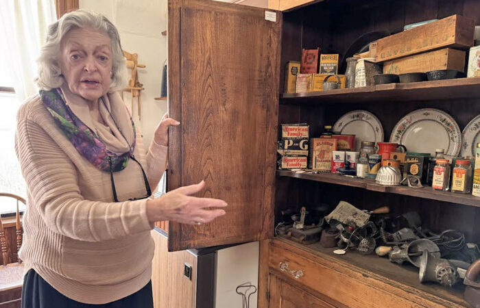 Elaine Egdorf shows of a cabinet filled with vintage spice and soap containers from products used in the early 19th century. (Karen Torme Olson)