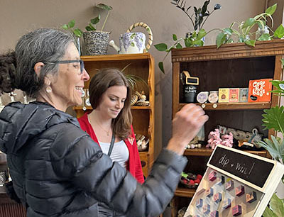 Pamela Abbott of Homewood, left, plays a game with Jackie Bassett of DIP at Gaia's in Homewood. DIP representatives were at the store April 10 promoting their hair care products. (Marilyn Thomas/H-F Chronicle)