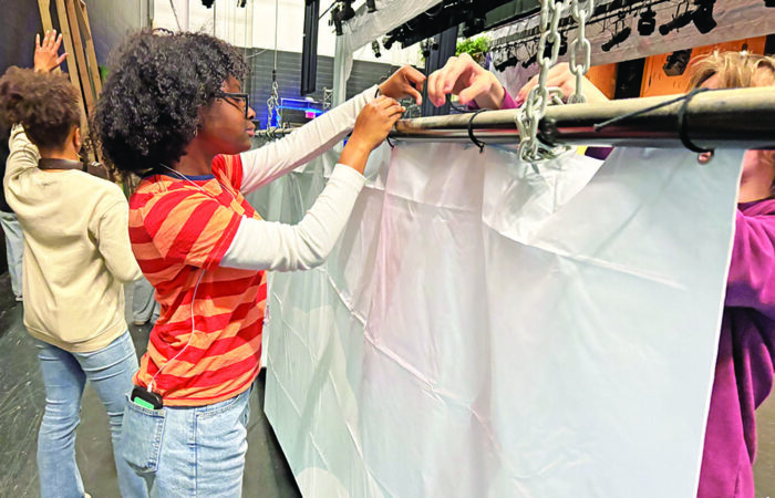 H-F 8_CMYK Senior Alayjah Andrews ties a backdrop to a pipe that will raise it to its full height of 17 feet. (Eric Crump/H-F Chronicle)