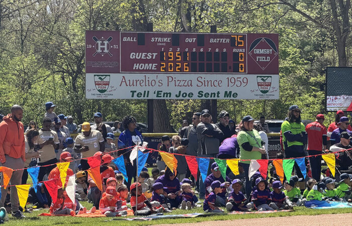 HBSL players, coaches and team parents watch the opening day ceremony from the outfield. (Nick Ulanowski / H-F Chronicle)
