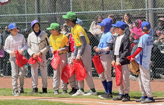Some of the HBSL players who are playing for the last time this season before aging out of the league are lined up on the first base line while HSBL President Angie Brandt recognizes them. (Nick Ulanowski/H-F Chronicle)