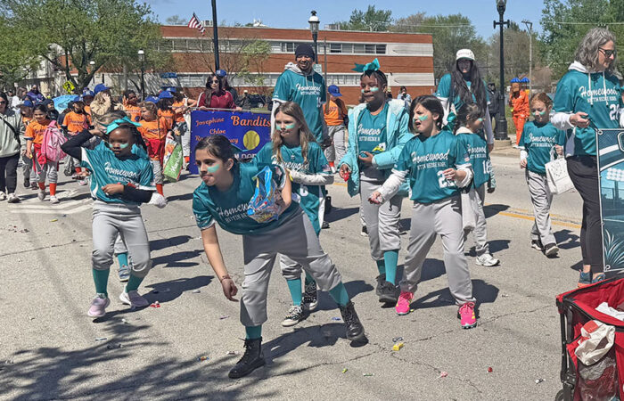 Players pitch candy to spectators, a tradition for the Homewood Baseball and Softball opening day parade. (Nick Ulanowski/H-F Chronicle)