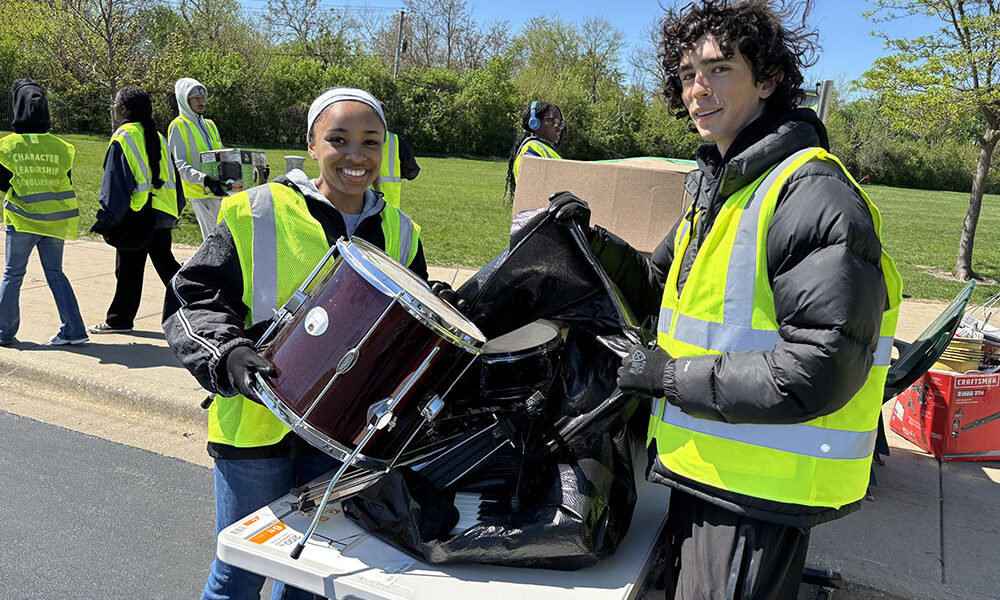 Homewood-Flossmoor High School students Laila Dyer, left, and Bennett Matthys, handled a donated drum set for the organization Helping Hands. (Marilyn Thomas/H-F Chronicle)