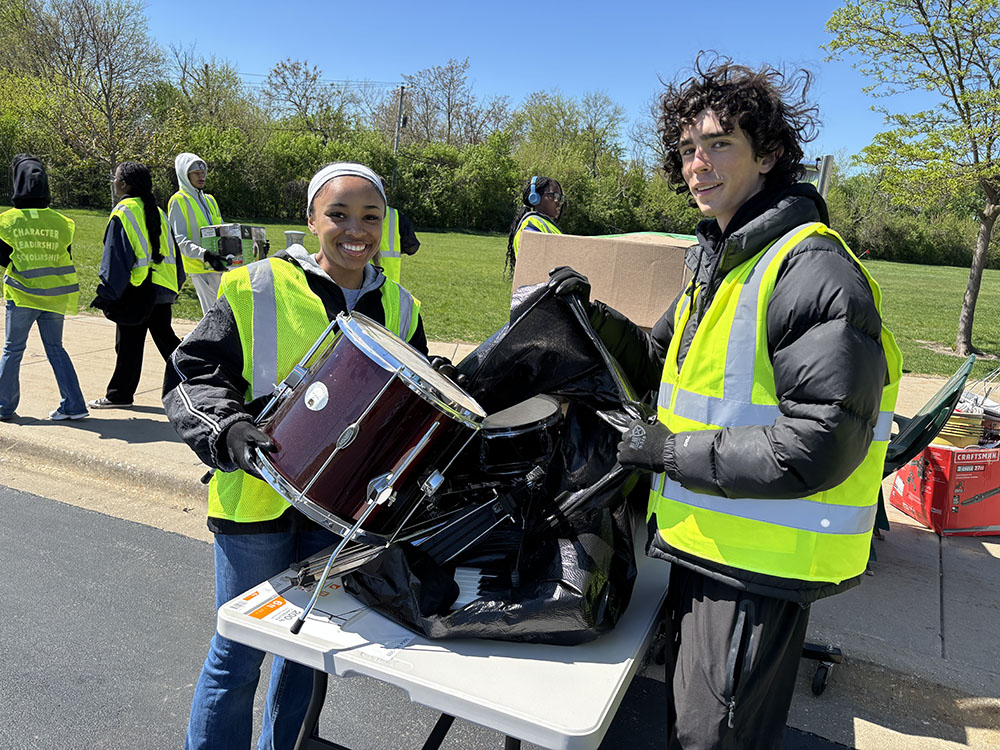 Homewood-Flossmoor High School students Laila Dyer, left, and Bennett Matthys, handled a donated drum set for the organization Helping Hands. (Marilyn Thomas/H-F Chronicle)