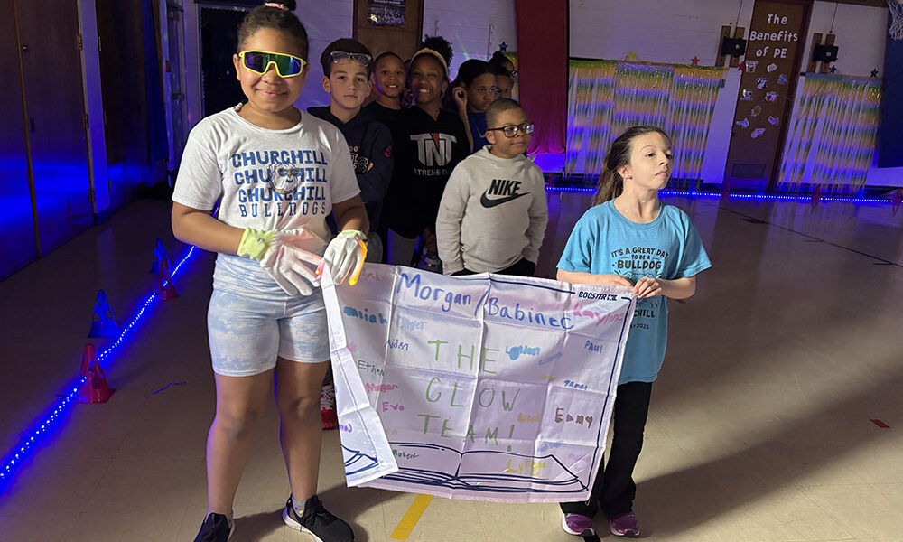 Jordyn Travis, left, and Emmy Roman carry the banner for their fourth grade class as the students prepare their start in the Glow Run fundraiser. (Marilyn Thomas/H-F Chronicle)