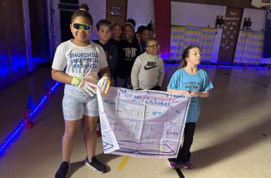 Jordyn Travis, left, and Emmy Roman carry the banner for their fourth grade class as the students prepare their start in the Glow Run fundraiser. (Marilyn Thomas/H-F Chronicle)