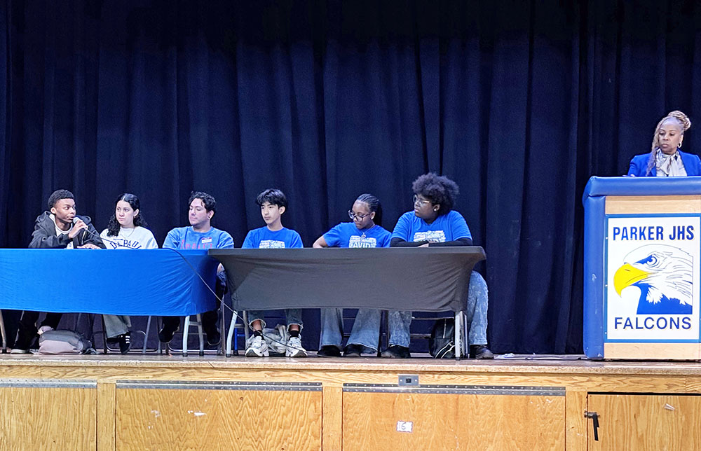 Parker Junior High Principal Ursula Parris, standing at podium, listens to introductions as students from DePaul University came to offer insights on college to Parker students at an assembly May 15. (Marilyn Thomas/H-F Chronicle)