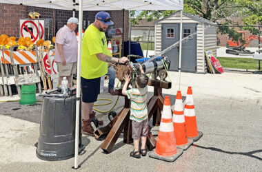 Homewood Public Works street maintenance worker Dan Spain opens a valve to a water main for a curious youngster during the 2026 Public Works Open House. (Nick Ulanowski / H-F Chronicle)