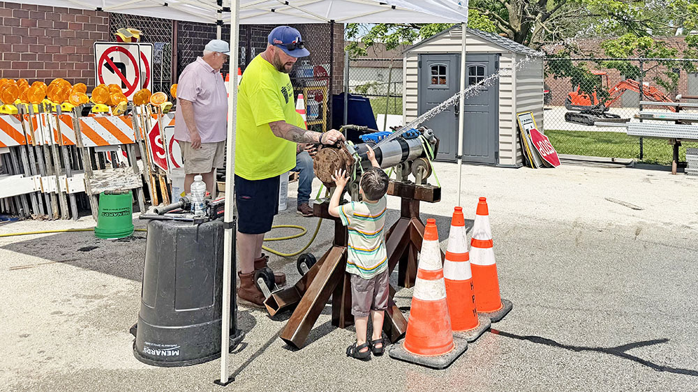 Homewood Public Works street maintenance worker Dan Spain opens a valve to a water main for a curious youngster during the 2026 Public Works Open House. (Nick Ulanowski / H-F Chronicle)