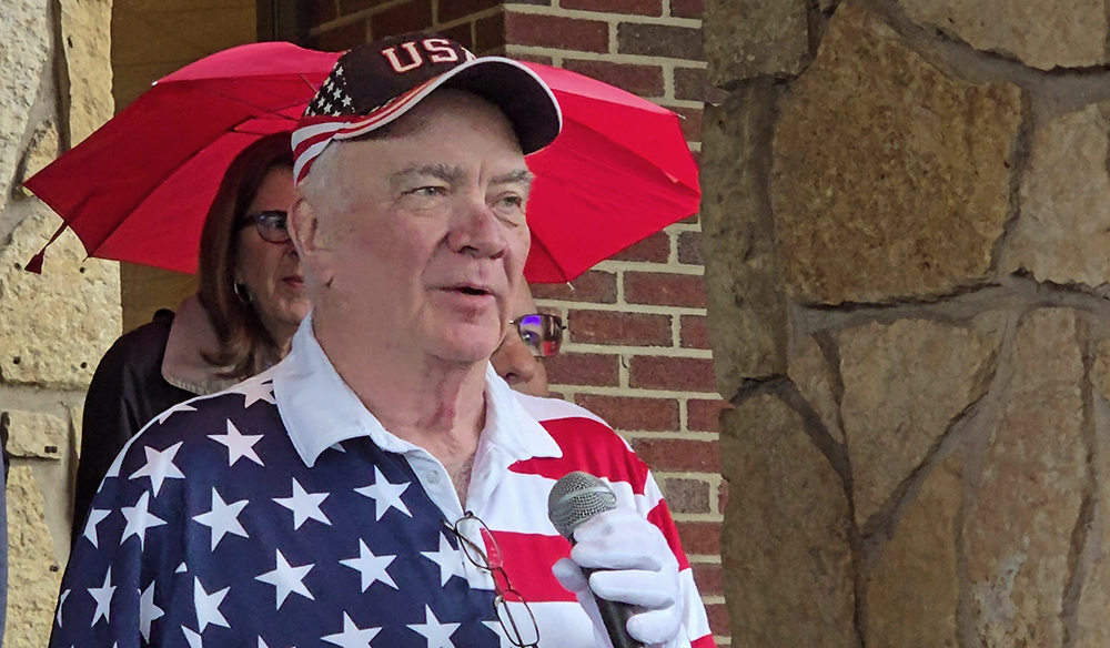 Golf outing organizer Dick Walsh addresses the crowd gathered under the entryway awning at the clubhouse at Idlewild on Sunday, May 24. (Eric Crump/H-F Chronicle)