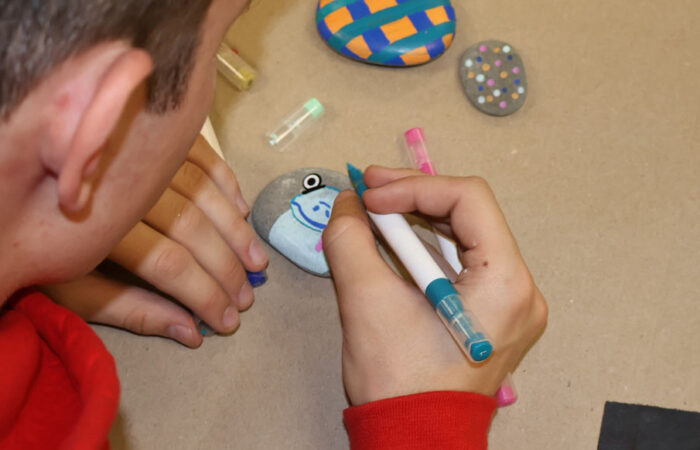 Pebbles and Pins#1_web Student Rocco Bonanotte paints on a rock during a community art initiative at Flossmoor Community Church. (Nuha Abdessalam/H-F Chronicle)