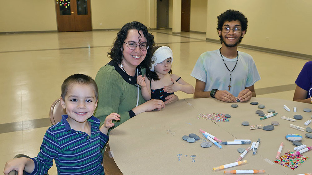Members of the Cruz family paints rocks together during “The H-F Pebbles & Pins Project” at Flossmoor Community Church, where folks were invited to create uplifting messages to place around Homewood and Flossmoor. (Nuha Abdessalam/H-F Chronicle)