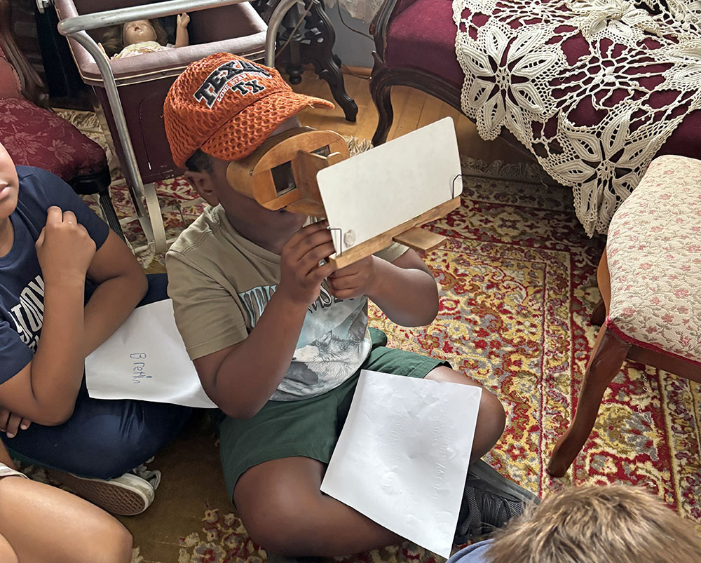 Ashton Bonsu is surprised by the 3-D image he sees using a stereoscope during a visit to the Dorband-Howe Museum in Homewood. (Marilyn Thomas/H-F Chronicle)