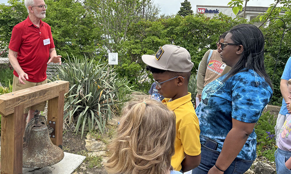 Volunteer Mark Leschuck shares the history of the old school bell in the garden of the Homewood Historical Society. (Marilyn Thomas/H-F Chronicle)
