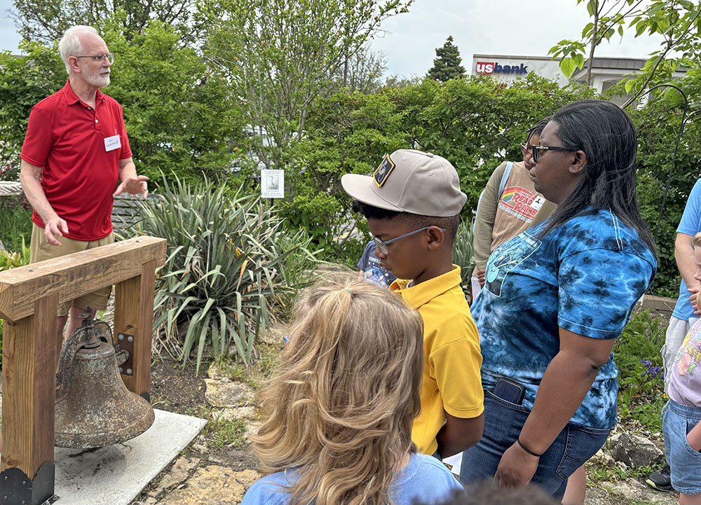 Volunteer Mark Leschuck shares the history of the old school bell in the garden of the Homewood Historical Society. (Marilyn Thomas/H-F Chronicle)
