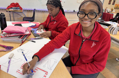 IJP 8th graders work on their poster projects for the FVM Time Machine lessons. Payton Thomas of Lansing (left) chose the U.S. Coast Guard as her subject while McKenzie Frison of Matteson crafts her poster on the U.S. Navy. (Karen Torme Olson)