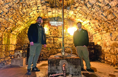 Thornton Distilling owner Andrew Howell, left, and head distiller Ari Klafter stand beside the well that takes water directly from the spring underneath the building. (Provided photo)