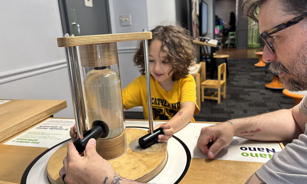 Rowan Lyday and his dad, Erik, try to attract magnets that are just one of the exhibits at the Homewood Science Center. (Marilyn Thomas/H-F Chronicle)