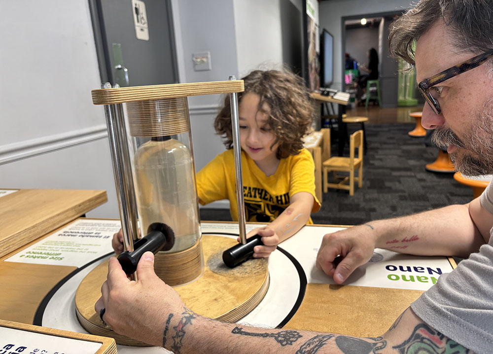Rowan Lyday and his dad, Erik, try to attract magnets that are just one of the exhibits at the Homewood Science Center. (Marilyn Thomas/H-F Chronicle)