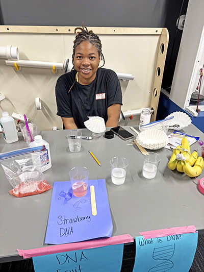 Braneya Harris, a senior at Homewood-Flossmoor High School, conducts an experiment for visitors at the Homewood Science Center on June 6. She is part of the STEAM Team of student volunteers. (Marilyn Thomas/H-F Chronicle)