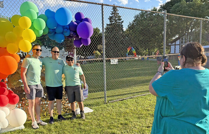 Therese Swigart, right, takes a photo of Schroeder Electric owner Jordan Schroeder, center, Schroeder‘s husband, Kory Risner, left, and his employee Mateo De La Rosa, right. (Nick Ulanowski / H-F Chronicle)