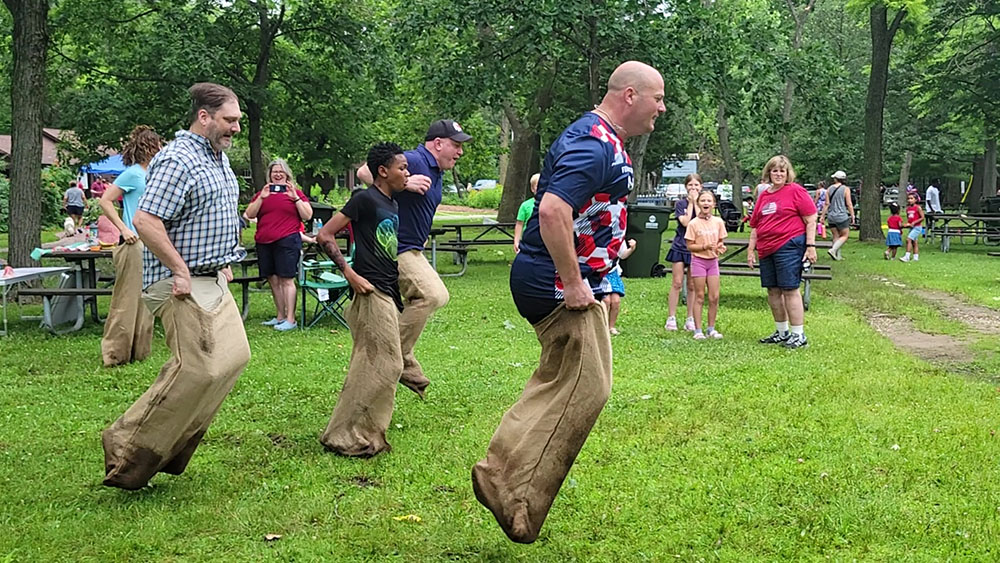 Adults take a turn at the one-legged race during the Izaak Walton community picnic on July 4. (Eric Crump/H-F Chronicle)
