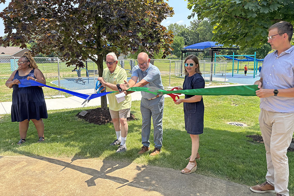 Ready to cut the ribbon to open the Irwin Park playground are Homewood Mayor Rich Hofeld, Homewood-Flossmoor Park District President Brent Bachus, center, and Flossmoor Mayor Michelle Nelson. They are joined by park district staff members Oralethea Davenport, left, and Zak Kerby, right. (Marilyn Thomas/H-F Chronicle)