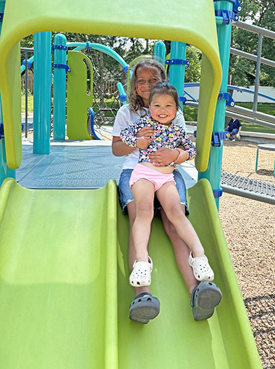 Addison McNeil, 8, holds her cousin, Ruby Rodriguez, 3, as they prepare to go down the slide. (Marilyn Thomas/H-F Chronicle)