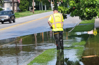 A Homewood Public Works crew works to clear a storm drain in the 1500 block of Ridge Road about two hours before the 4th of July parade would pass the spot. The effort was successful and Ridge Road was dry by the time the parade arrived. (Eric Crump/H-F Chronicle)