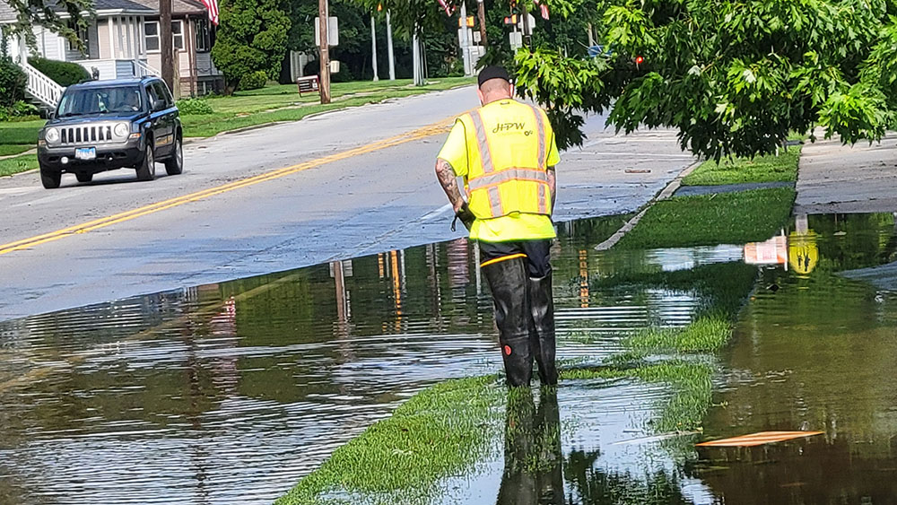 A Homewood Public Works crew works to clear a storm drain in the 1500 block of Ridge Road about two hours before the 4th of July parade would pass the spot. The effort was successful and Ridge Road was dry by the time the parade arrived. (Eric Crump/H-F Chronicle)